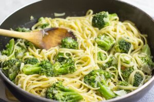 A frying pan full of broccoli pasta with a wooden spoon in it | Hurry The Food Up