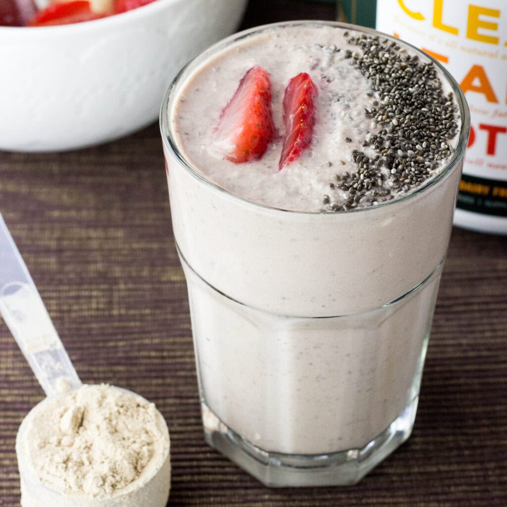 Strawberry and cottage cheese smoothie in a glass with protein powder nearby