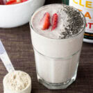 Strawberry and cottage cheese smoothie in a glass with protein powder nearby