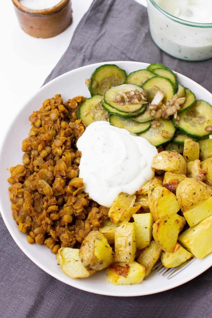 The Buddha bowl is served with cucumber salad on the table on a plate with tea towel, salt and sauce #vegetable broth #brown lentils | 