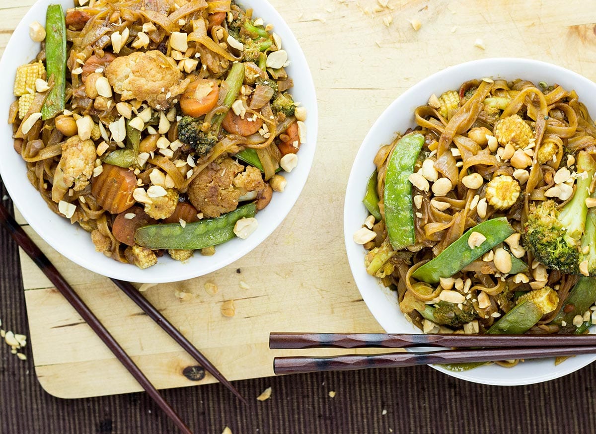 Two bowls of peanut stir fry with chopsticks