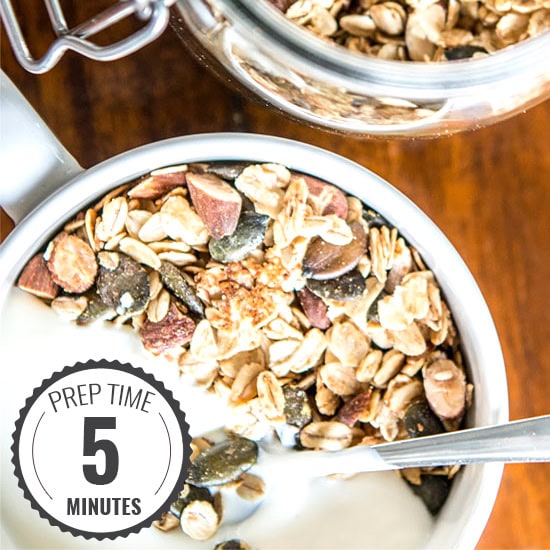 Granola in a bowl with yogurt on the side and a spoon