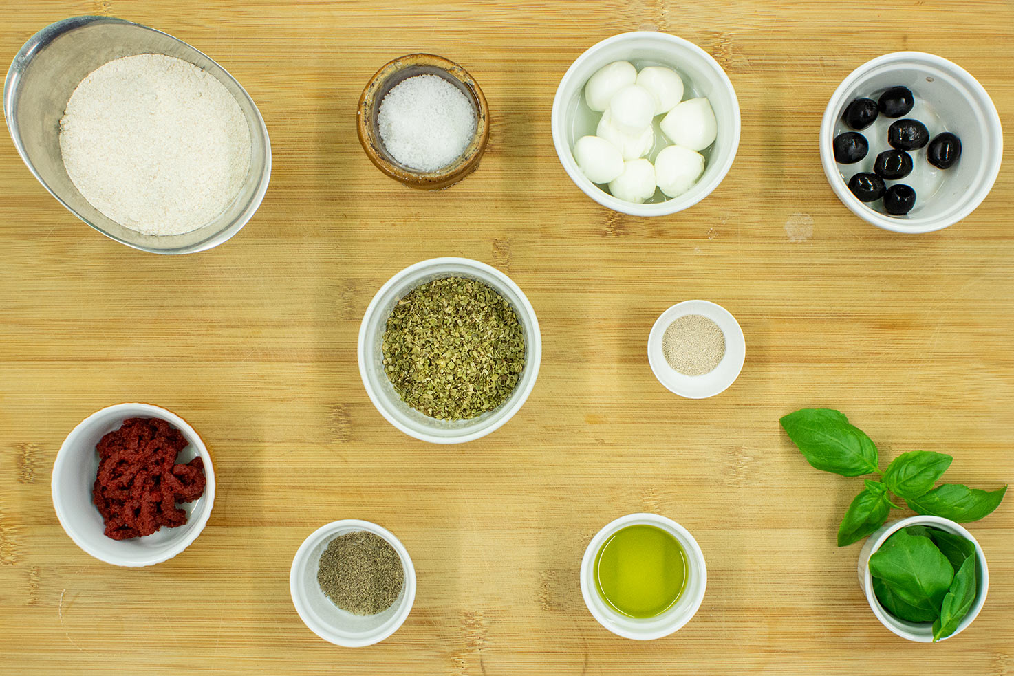 The dish ingredients are on the chopping board - flour, water, olive oil, tomato paste, Italian herbs, mozzarella #olives #basil leaves | 