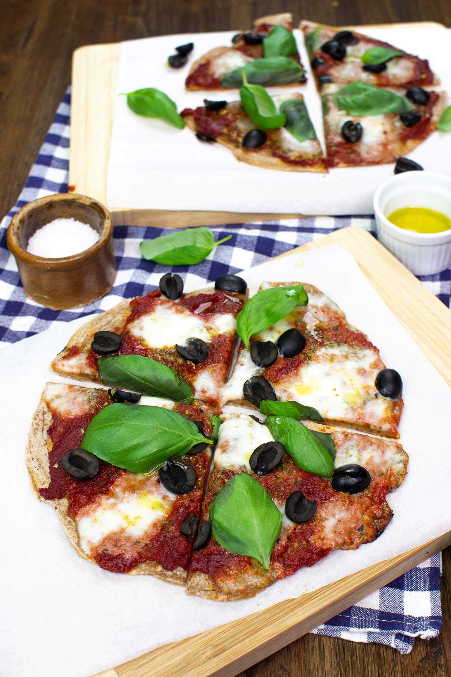 Two Pancake Pizzas are on the black table on two wooden boards with towel, salt and olive oil #flour #water | 