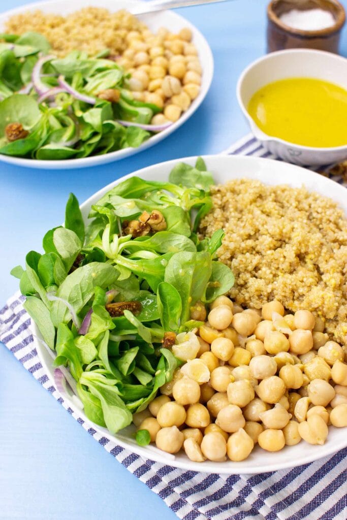 The meal with corn salad are on the table on 2 plates with towel, salt and dressing #olive oil #white vinegar | 