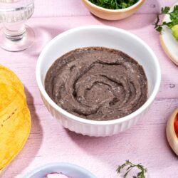 Refried beans are served in the white bowl that is on the table with tortillas, cilantro, sliced radishes etc.| Hurry The Food Up