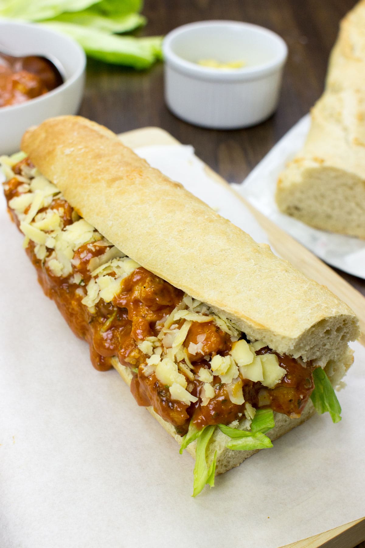 Vegetarian coronation chicken lies on the wooden board, which is covered by white paper. Around it, there are some bowls and bread | Hurry The Food Up