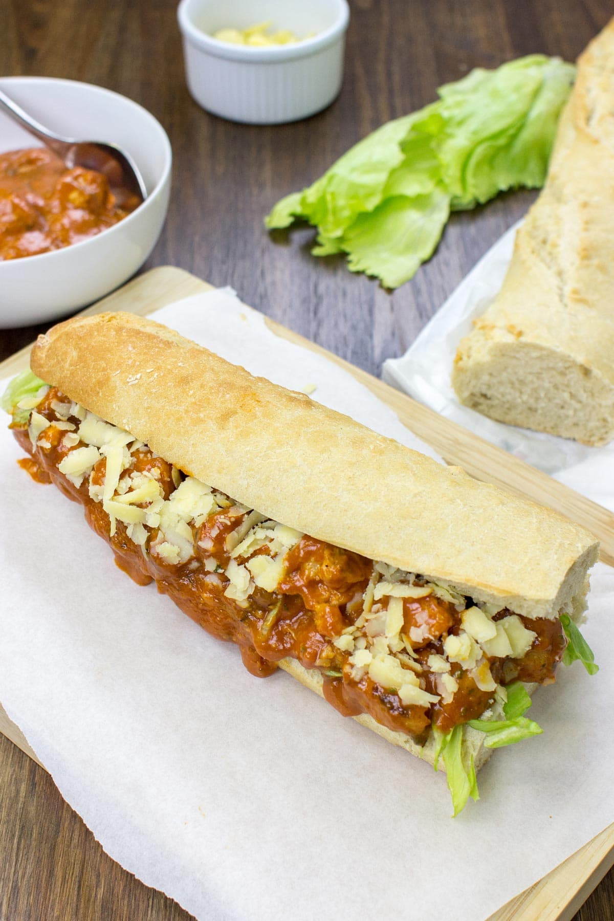 Vegetarian coronation chicken lies on the wooden board, which is covered by white paper. Around it, there are some bowls and bread | Hurry The Food Up