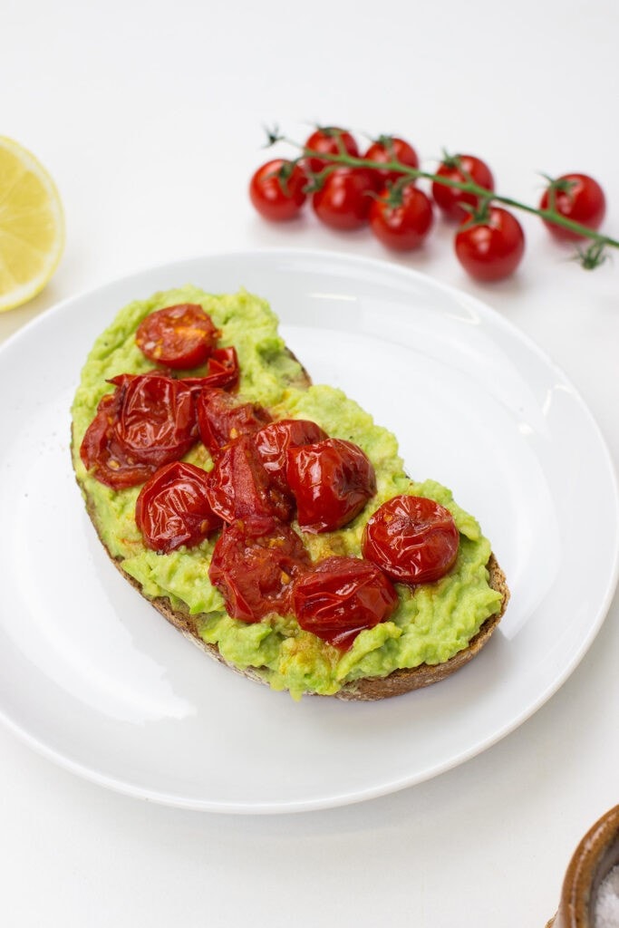 Tomato Avocado Toast is on the plate on a table with salt, lemon and cherry tomatoes #bread #olive oil | 