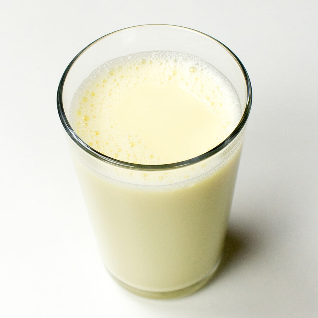A glass of almond milk on white surface