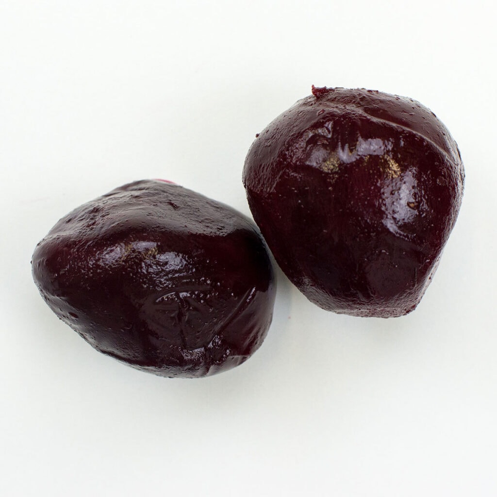Two beetroots on white surface