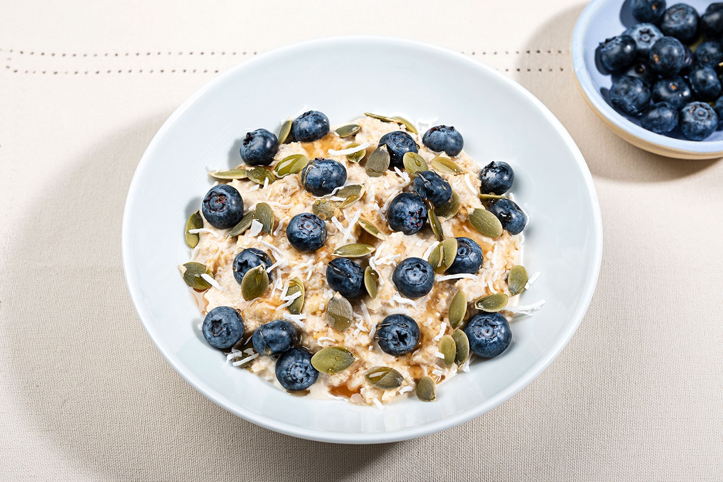 The Bircher oats is in a bowl topped with blueberries, pumpkin seeds and coconut flakes | Hurry The Food Up