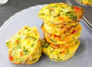 4 breakfast egg muffins, spicy pepper flavour, on a grey plate, three of them are piled on each other. | Hurry The Food Up