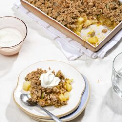 A serving of healthy breakfast crisp alongside a tray of the bake and a bowl of yoghurt. | Hurry The Food Up