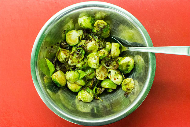 Brussel sprouts being mixed with balsamic vinegar in a bowl
