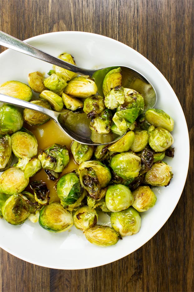 The balsamic-soaked sprouts are served in a white dish on a brown table