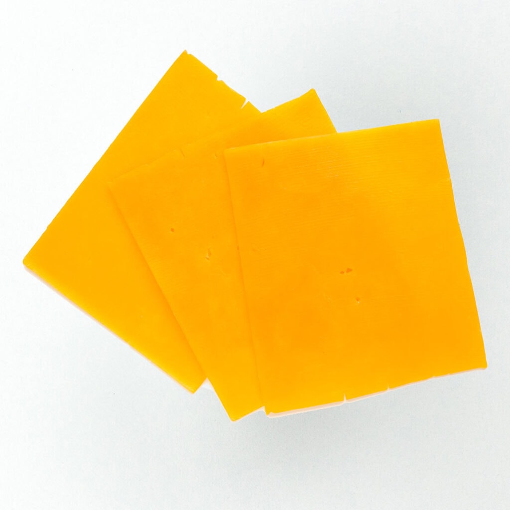 Cheddar slices on white surface