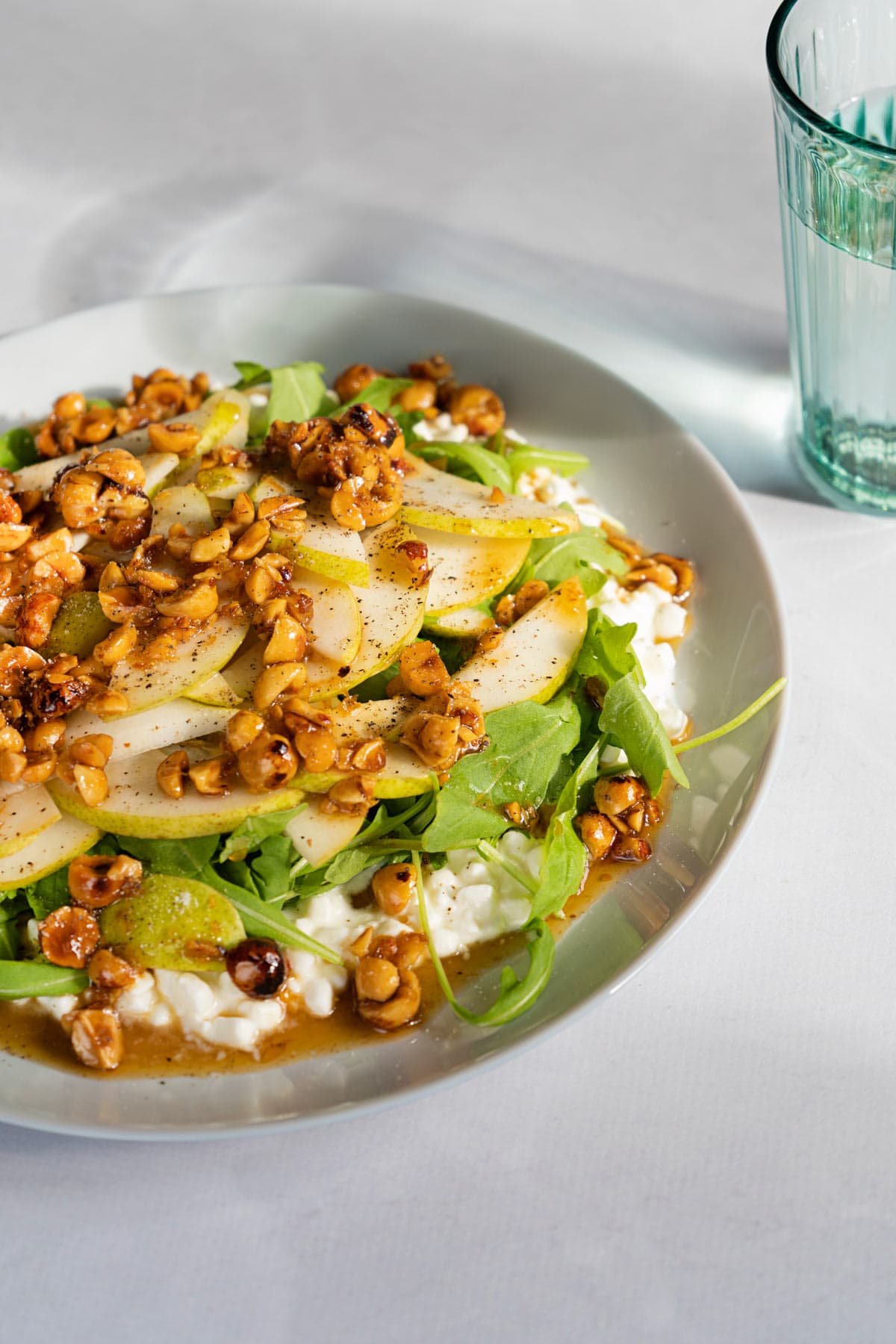 Cottage cheese salad served on a white plate which is on a light surface. Next to it there is a glass of water | Hurry The Food Up