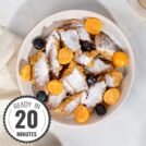 A birds eye view of a bowl of schmarrn breakfast, with fruit and yogurt, on a white marble surface with a time stamp in the bottom left hand corner | Hurry The Food Up