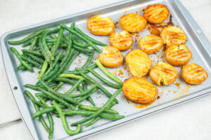The process of laying the whole green beans and seasoning with lemon juice on a baking sheet | Hurry The Food Up