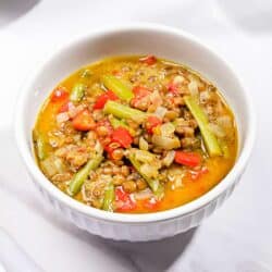 A bowl of curried lentil soup with coconut milk on a white surface | Hurry The Food Up