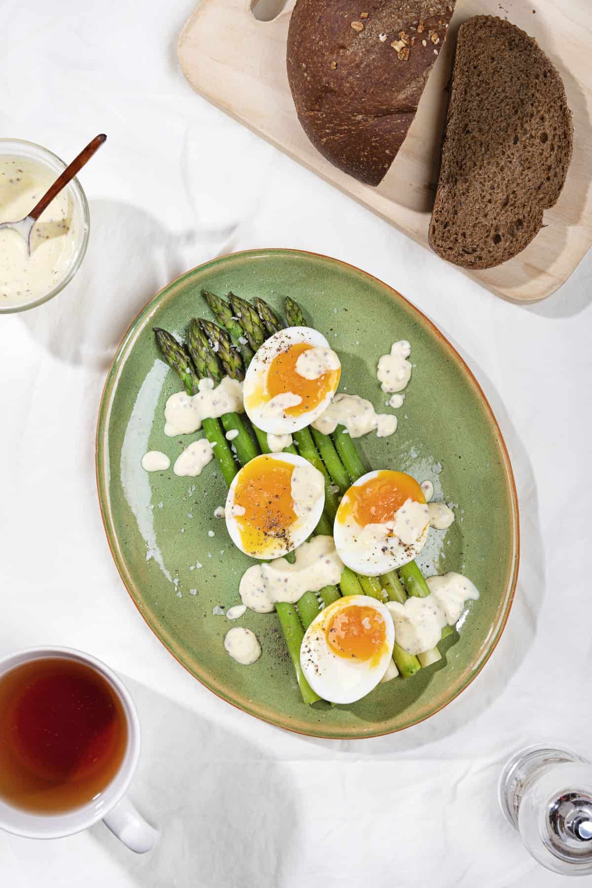 A breakfast of eggs and asparagus drizzled with dijon sour cream sauce, with sliced rye bread on the side | Hurry The Food Up