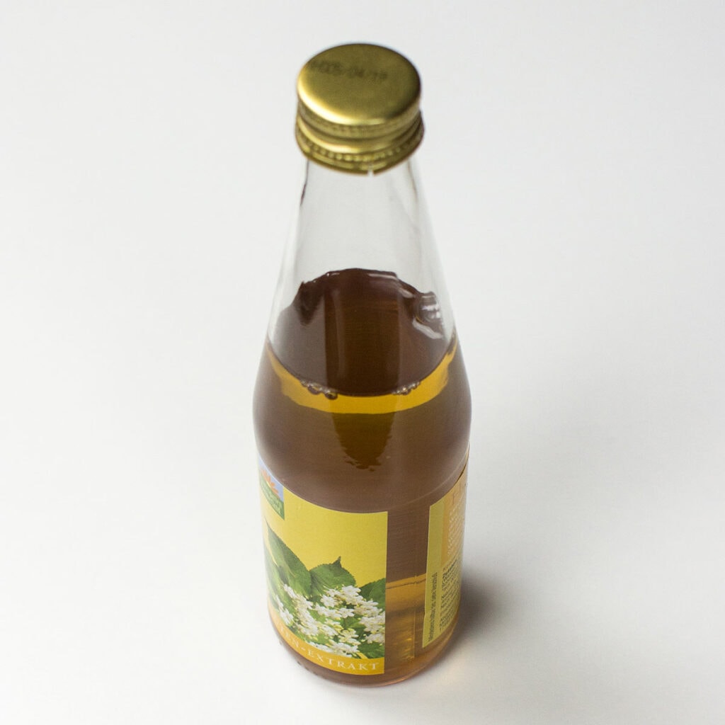 A bottle of elderberry syrup on white surface