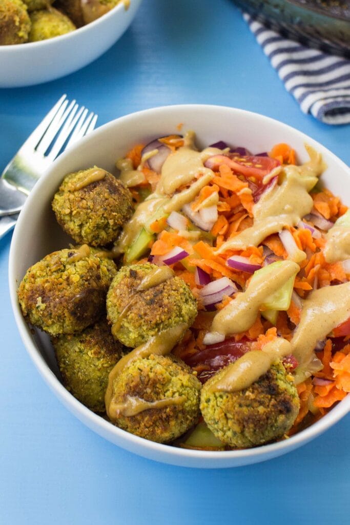 Falafel and Fake Tahini Salad is served in the bowl and two forks on the blue table | Hurry The Food Up