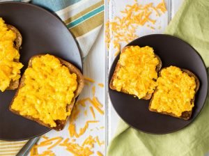Bread with perfect scrambled eggs with cheese lie on the black plate that is on the napkin | Hurry The Food Up