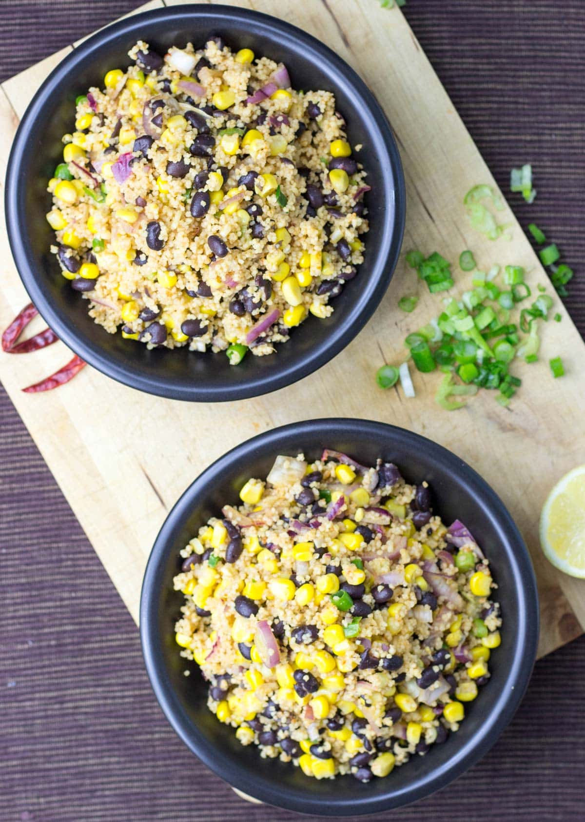 Two black bowls with high protein black bean salad with corn, that are on the wooden surface | HurryTheFoodUp