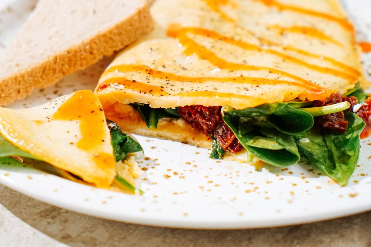 High Protein Omelette, topped with sriracha, salt and black pepper which is on the light plate | Hurry The Food Up
