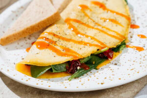 The process of serving omelette on a plate, topped with sriracha, salt and black pepper | Hurry The Food Up