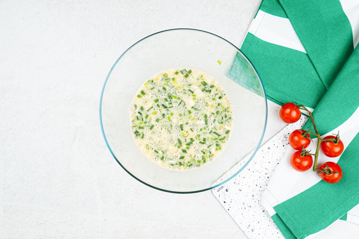 The process of mixing eggs, sliced scallions, season with salt and black pepper in the medium bowl | Hurry The Food Up