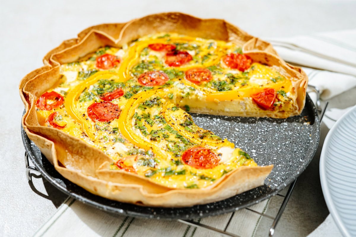 The high-protein tortilla quiche lies on the black plate, which is on the metal grating | Hurry The Food Up