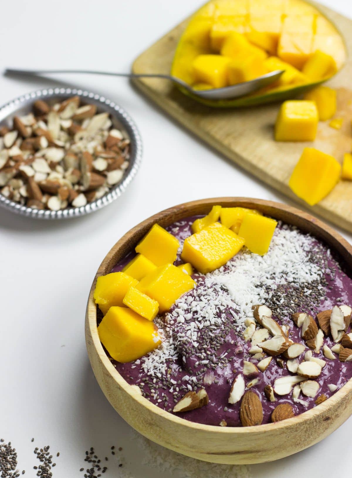A bowl of acai, chopped mango and a dish of chopped nuts | Hurry The Food Up