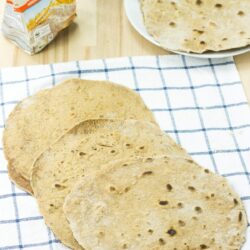 Flour Tortillas lie on the checkered tablecloth. Next to it there are a package of flour, olive oil and a plate with tortillas | Hurry The Food Up