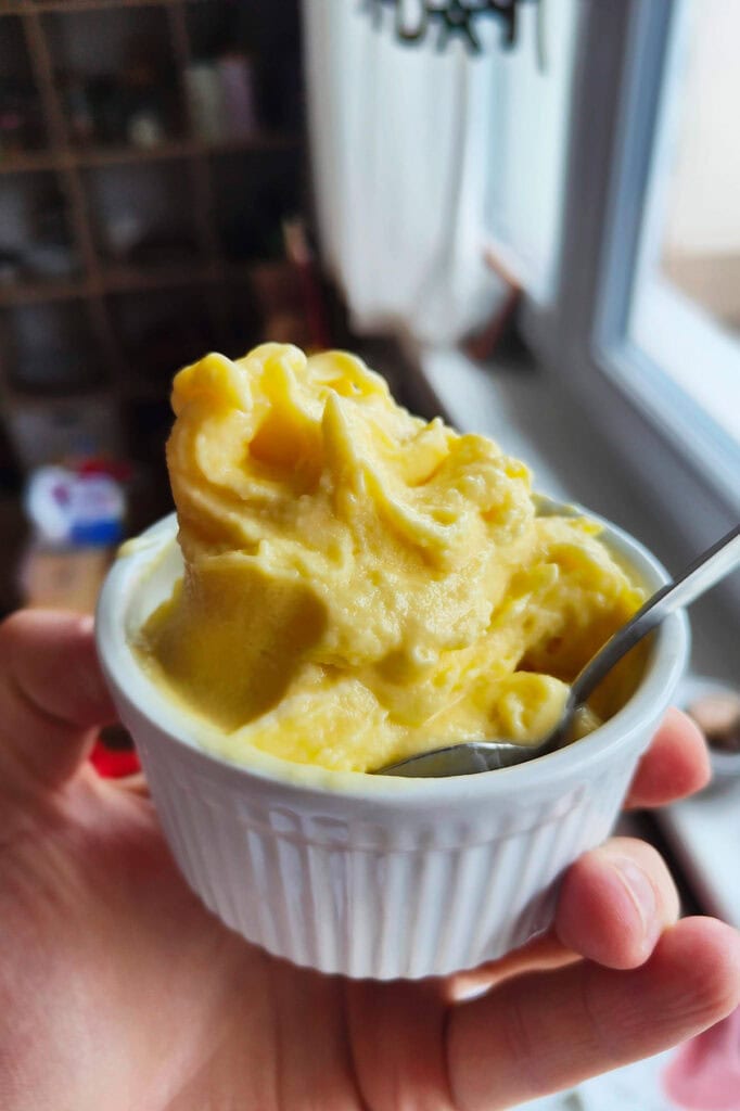 A ramekin of ice cream in a hand