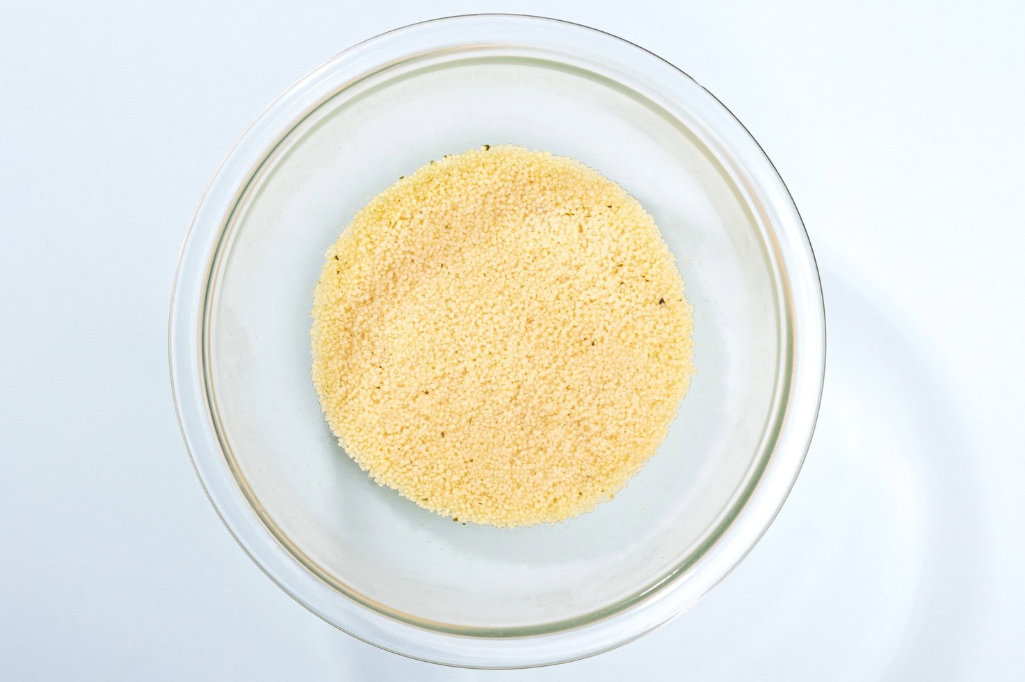 A bowl of uncooked couscous on a plain surface | Hurry The Food Up