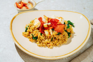 Easy High-Protein Millet Pilaf is on the light plate with Baked Feta on the top of it | Hurry The Food Up