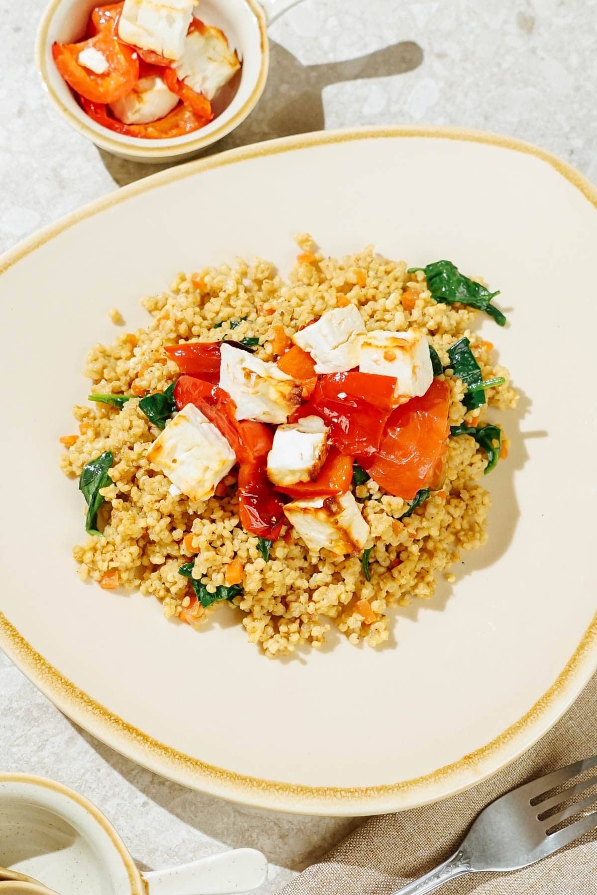 Easy high-protein millet pilaf is on the light plate with baked feta on the top of it | Hurry The Food Up
