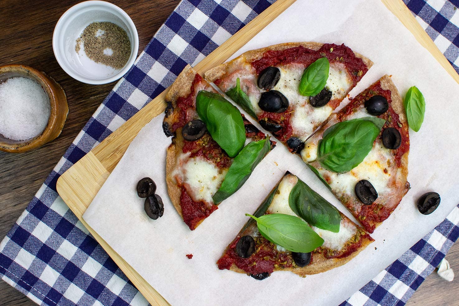 Two Pizzas are on the black table on two wooden boards with towel, salt, pepper and olive oil #dried yeast #tomato paste | 