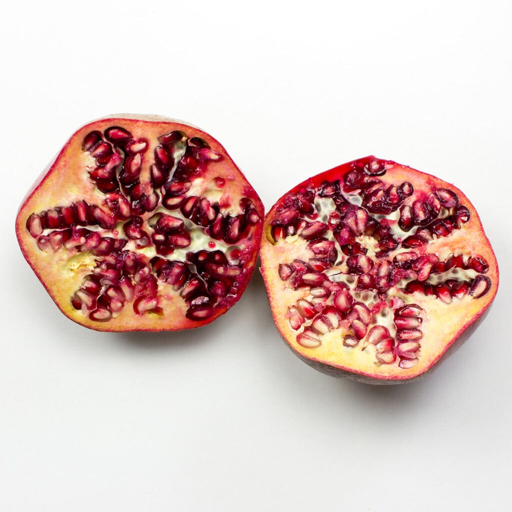 Two pomegranate halves on white surface