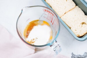 A plastic jud and a loaf tin with some slices of bread are on the light surface | Hurry The Food Up