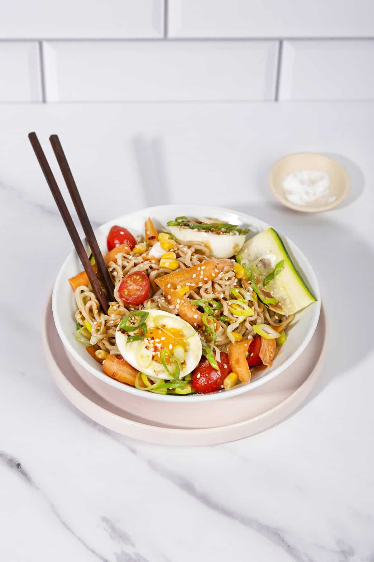 A bowl of soba noodles with egg, veggies and sesame seeds. A pair of chopsticks are stuck into it. | Hurry The Food Up