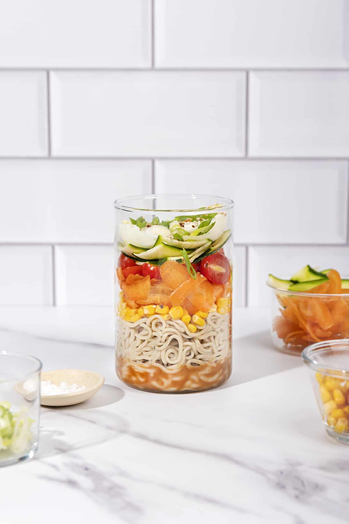 An open jar in the process of being layered with lots of ingredients including zucchini, carrot, salt | Hurry The Food Up