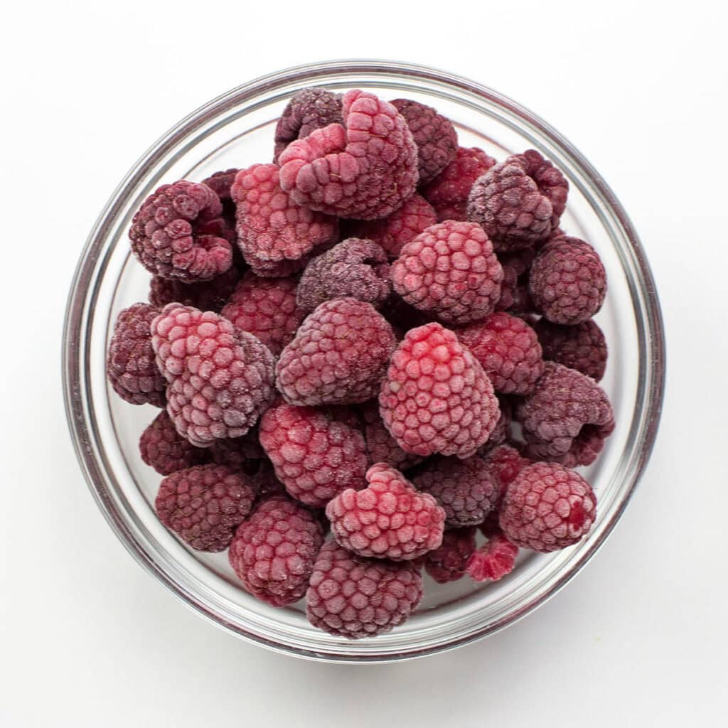 A bowl of raspberries on white surface