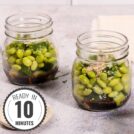 On a stone table sits two mason jars containing cucumber and edamame smashed salad with a time stamp in the bottom left hand corner | Hurry The Food Up