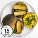 A Tofu Pesto Sandwich with crispy bread, layered with marinated tofu, fresh greens, and a generous spread of vibrant pesto, sits on a plate with a timestamp in the left corner.