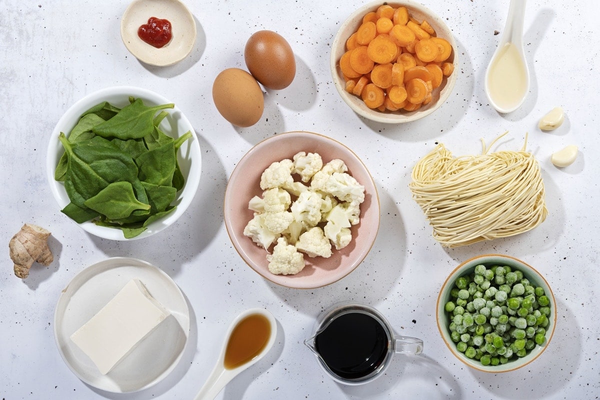 Ingredients for a drop egg soup including, ginger, garlic, sesame oil, vegetable broth, low sodium, soy sauce, sriracha, carrots, cauliflower florets egg noodles, spinach etc. | Hurry The Food Up