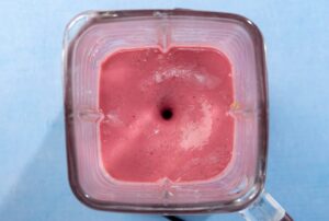 A birds-eye view of a square blender, blending a vegan blackberry smoothie on a blue table | Hurry The Food Up